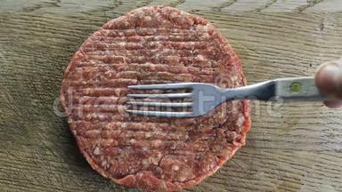 粗圆的切块放在一块木板上，木板上用一个叉子叉起汉堡，从上面拍摄